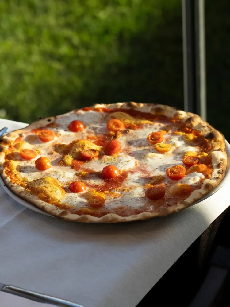 Pizza cotta nel forno a legna con pomodorini e mozzarella